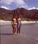Photo of a couple  on a beach 
with a long empty stretch of sand in the background.